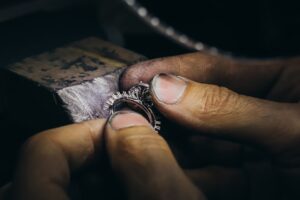 A person's hands examining gold and gemstone rings displayed on a jewelry tray.